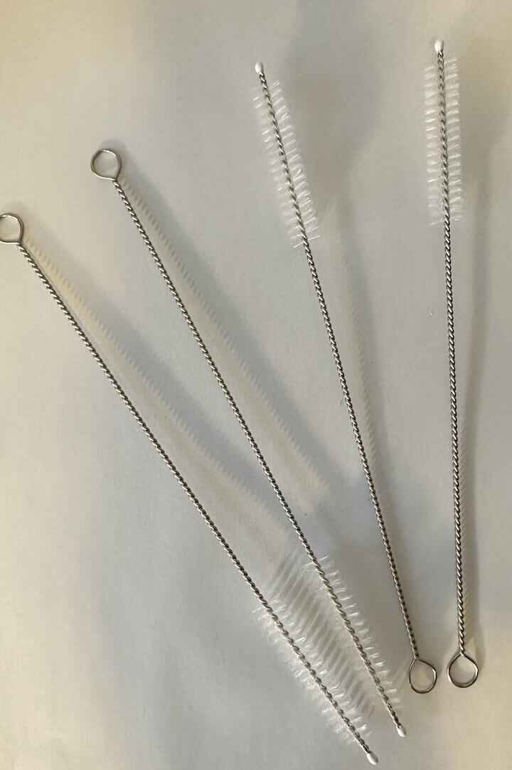 Vier metalen rietjesborstels op een witte achtergrond.