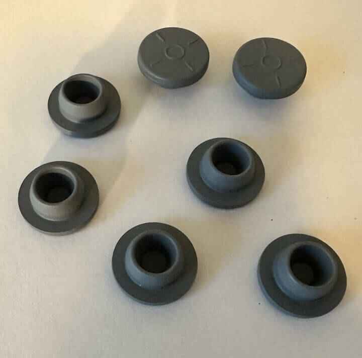 Zeven grijze rubberen doppen op witte achtergrond.